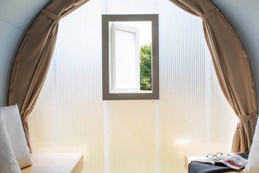 Interno minimalista con due letti, finestra aperta e luce naturale.