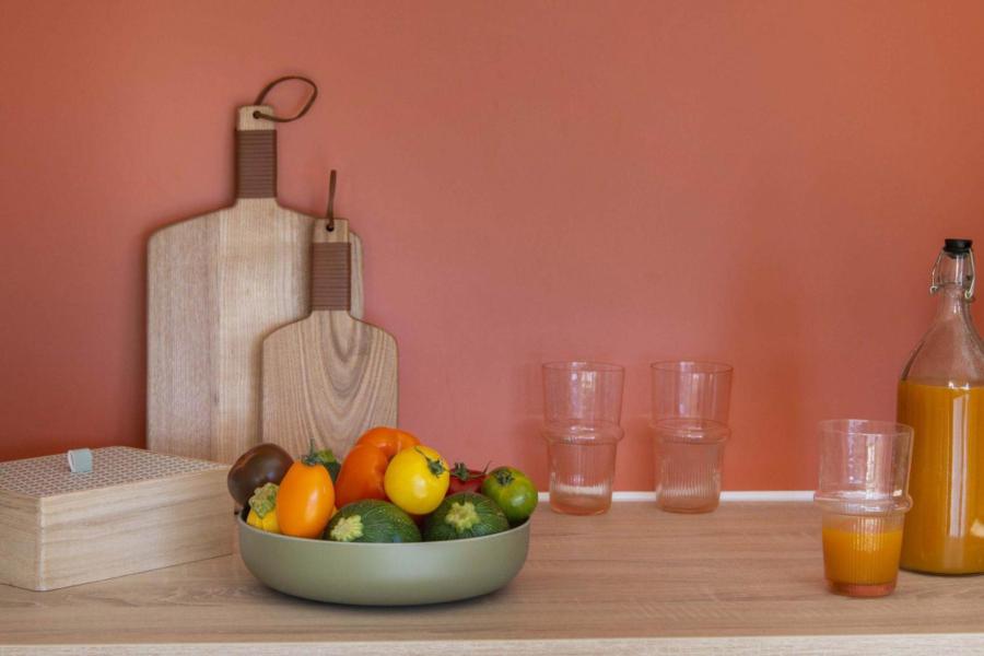 Cucina con frutta, taglieri e succo d'arancia su sfondo arancione.
