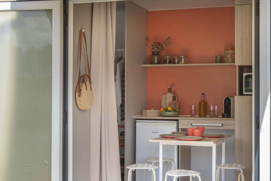 Interno di una piccola cucina moderna con tavolo e sedie bianche.