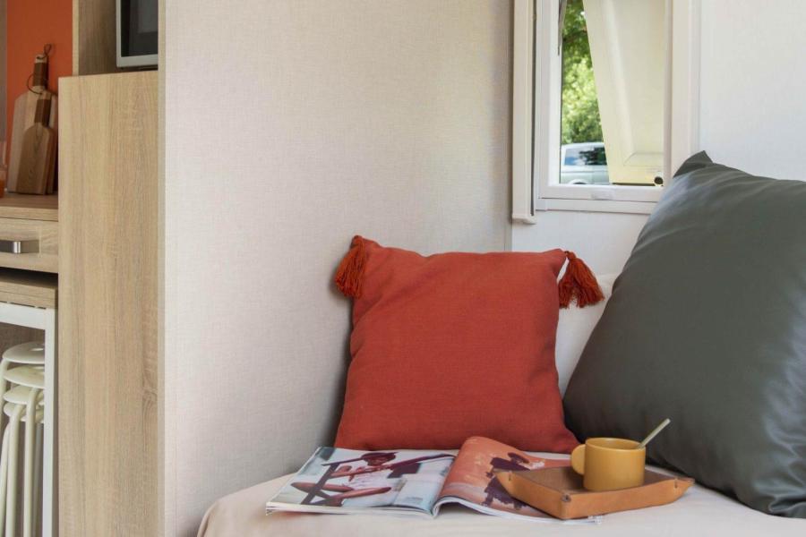 Interno accogliente con cuscini colorati, rivista e tazza su un divano.
