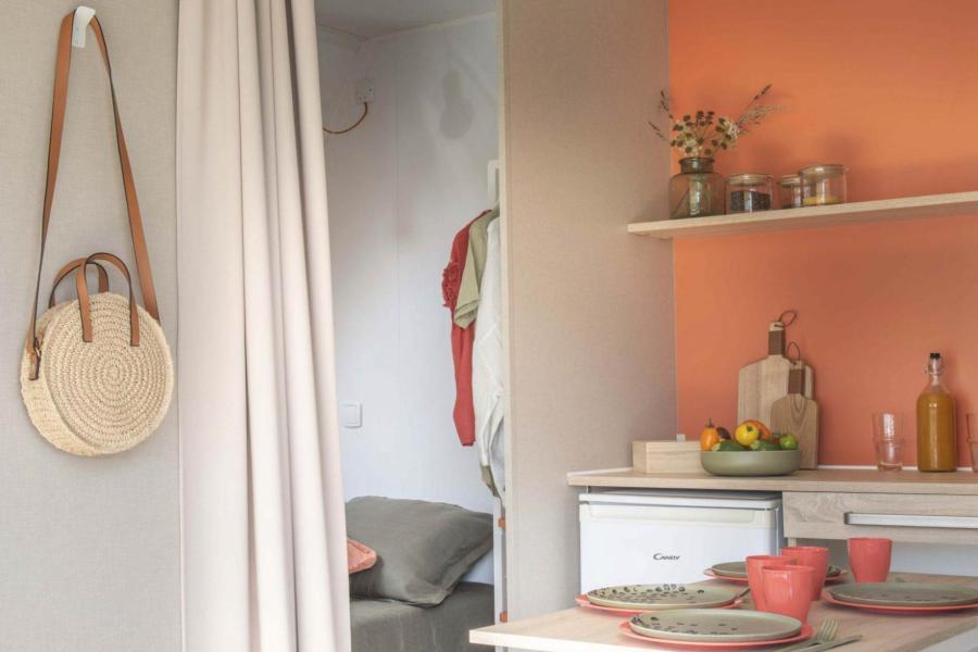 Interno accogliente con cucina, tavolo e zona letto separata da tenda.